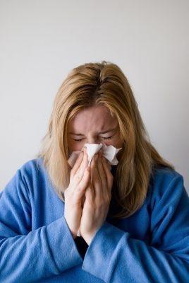 Eine Frau, die sich die Nase putzt. Eine Nasennebenhöhlenentzündung (Sinusitis) kann zu einer großen Belastung führen.