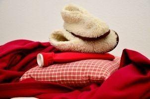 Decke, Kissen, Wärmflasche und Fellschuhe, um einer Blasenentzündung vorzubeugen