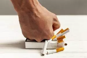 Mensch, der eine Zigarettenschachtel zerdrückt, die er nicht mehr benötigt, da er mithilfe von Hypnose aufgehört hat zu rauchen