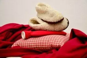 Decke, Kissen, Wärmflasche und Fellschuhe, um einer Blasenentzündung vorzubeugen
